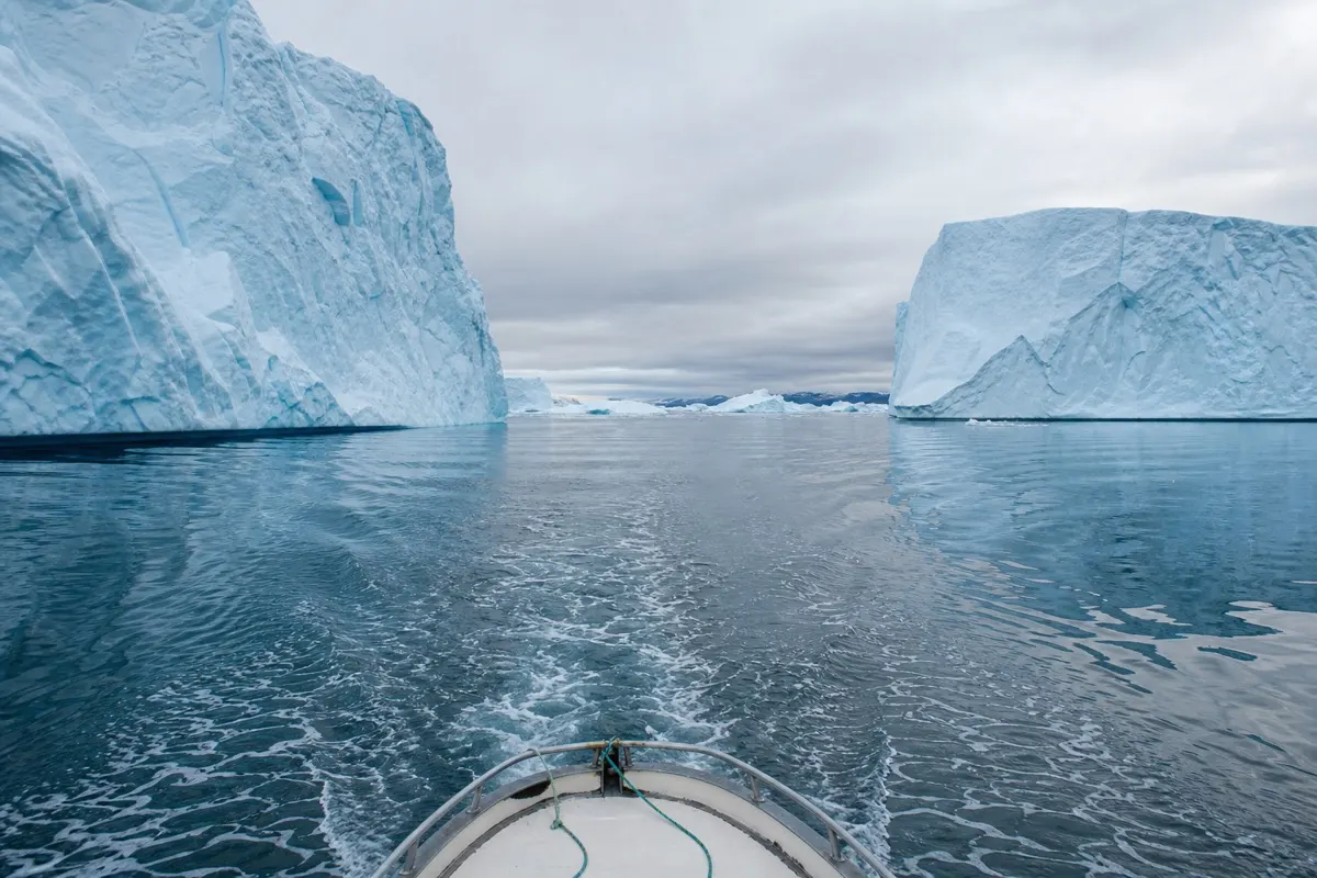 Small tour boat cruising between icebergs in Disko Bay