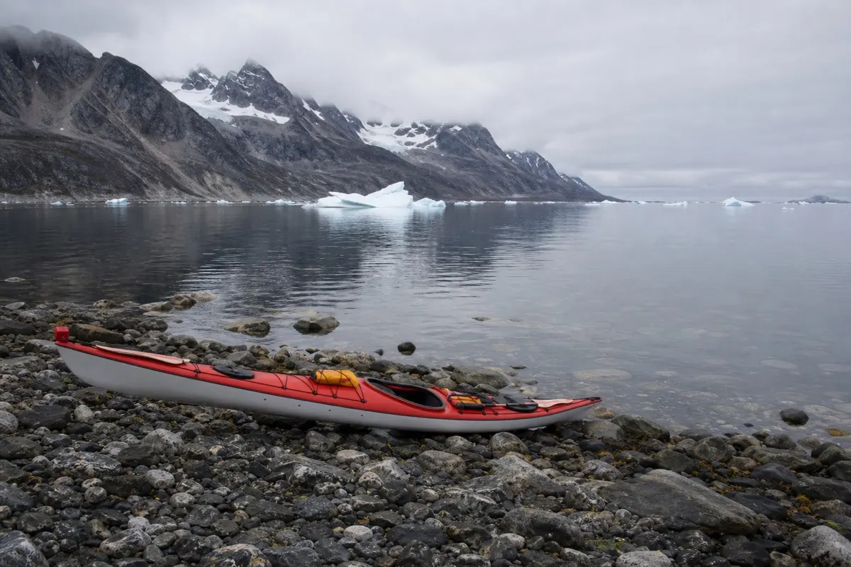 Sea kayaker paddling among icebergs